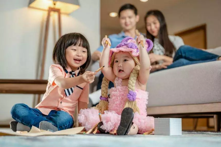 Brother was playing with his sister.He raised his hand and laughed at the little siste