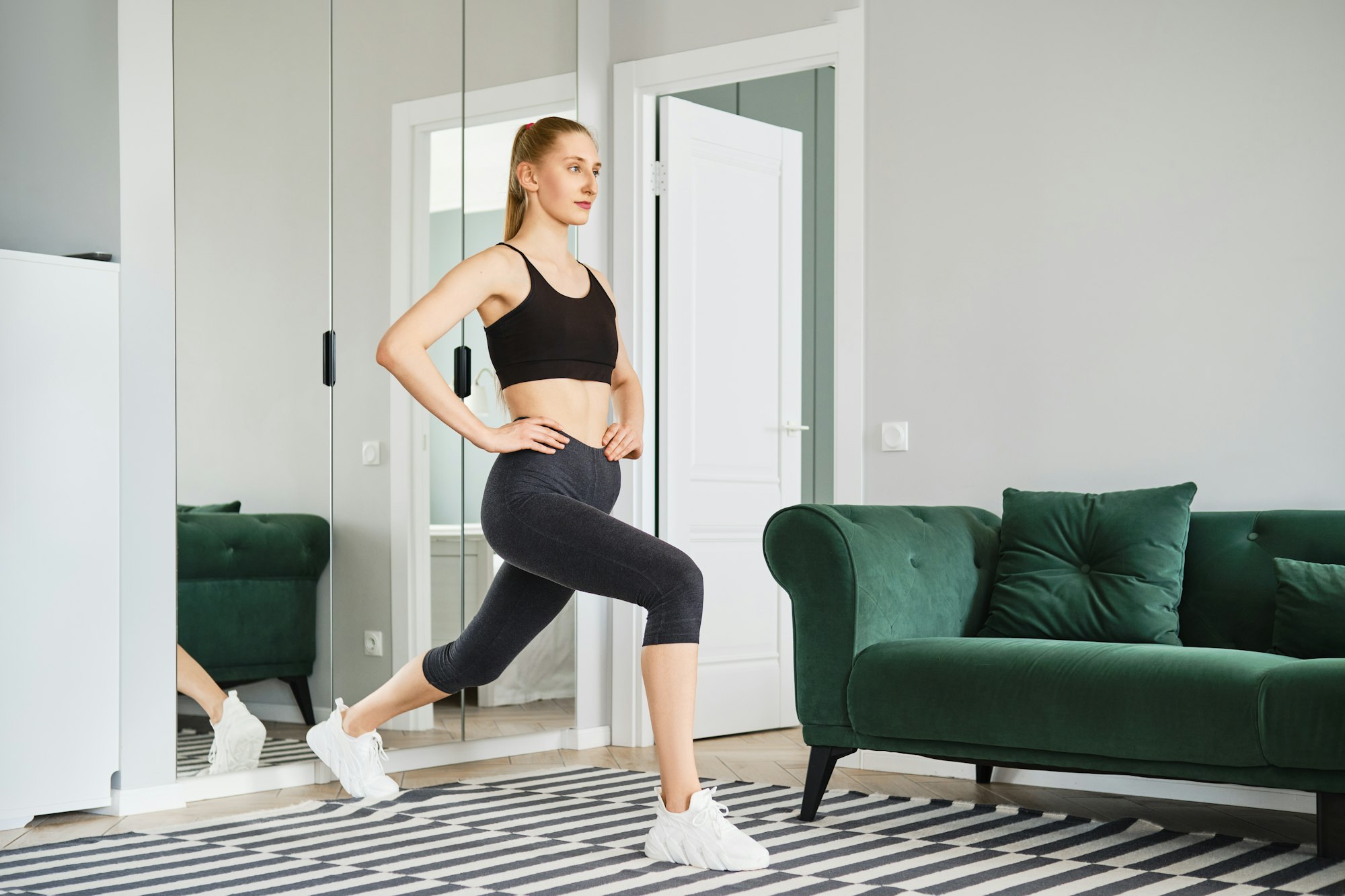 Young woman in sport clothing does sports at home every day